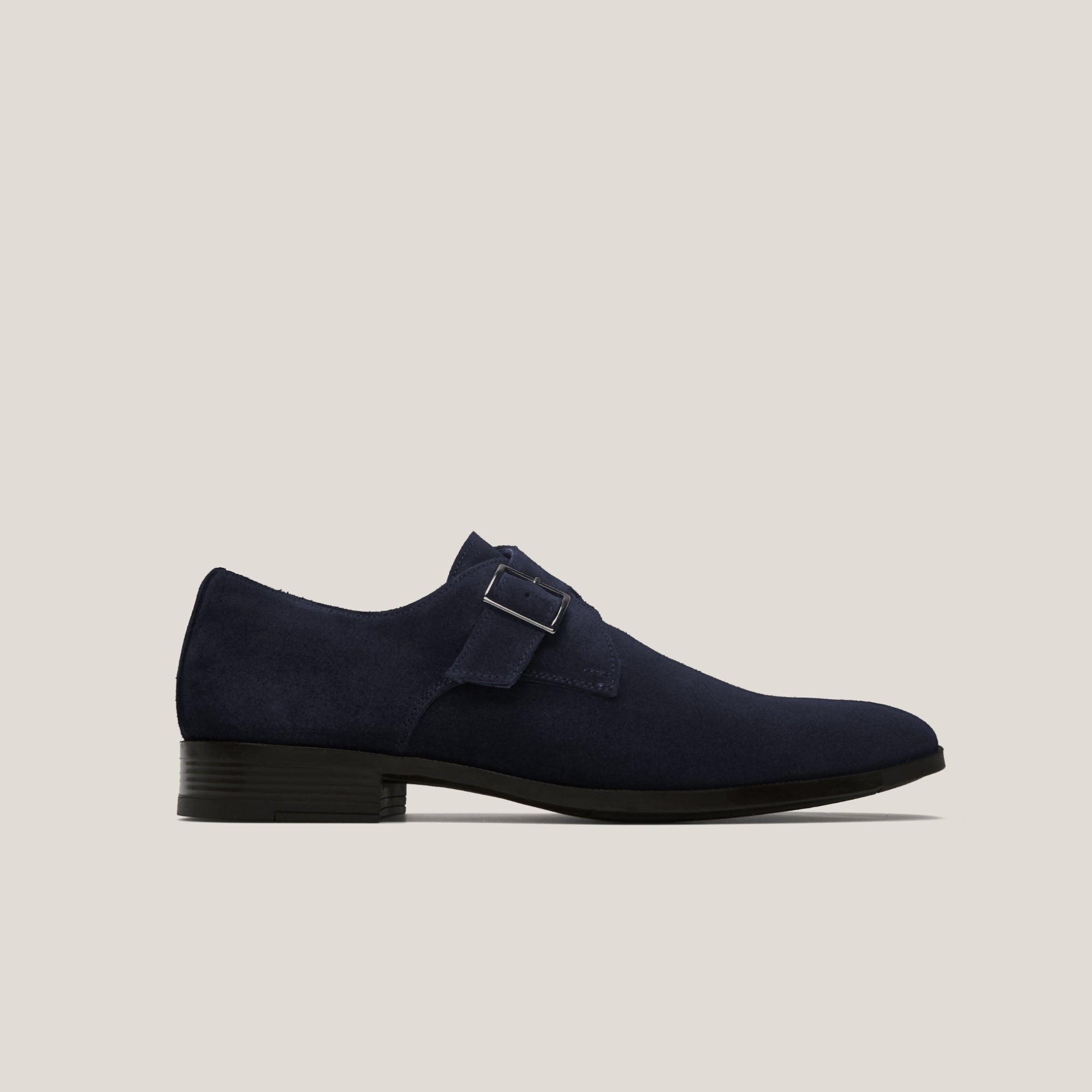 A single dark navy suede monk strap shoe with a silver buckle and a black sole.