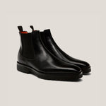 Pair of black leather Chelsea boots on a light gray background