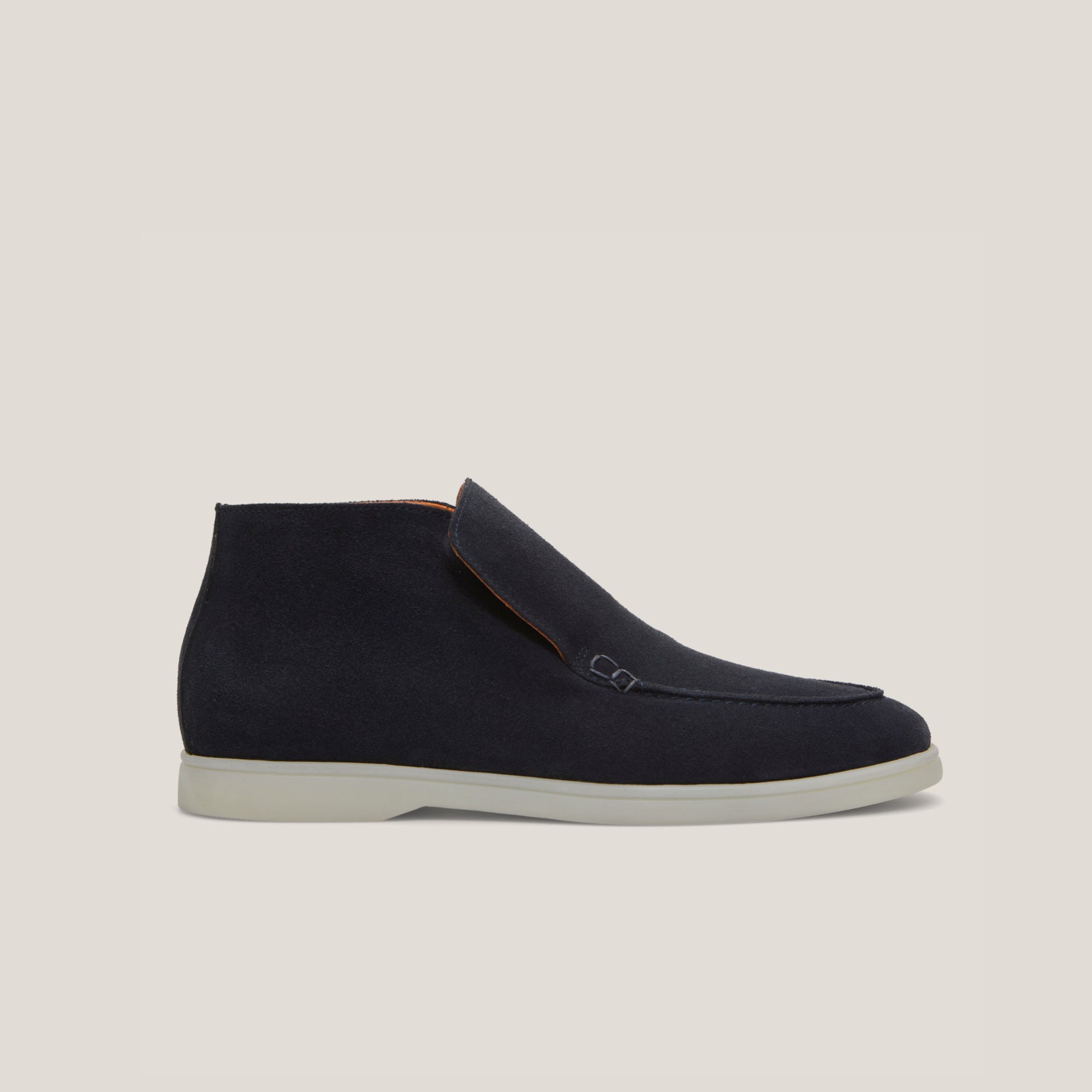 A dark navy suede ankle loafer boot with a white sole.
