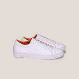 White leather sneakers with orange lining on a light gray background