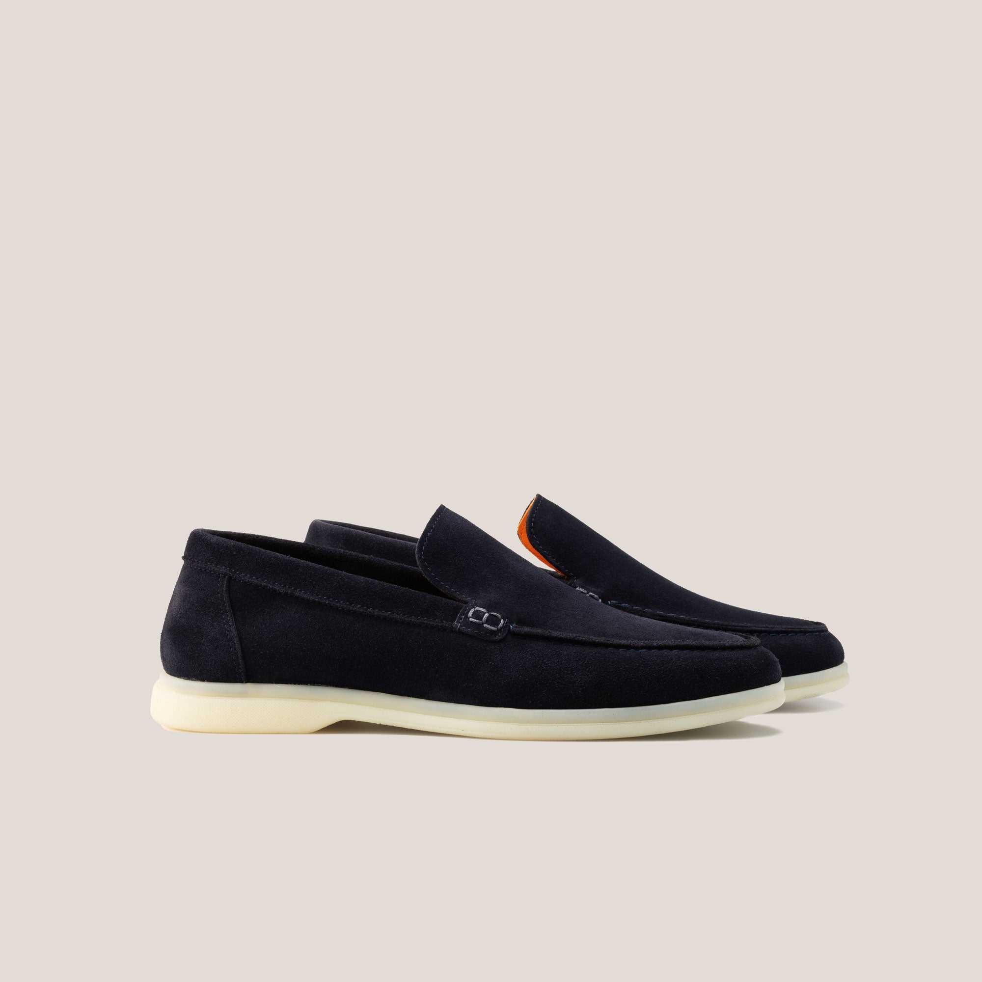 A pair of dark navy suede loafers with a white sole.