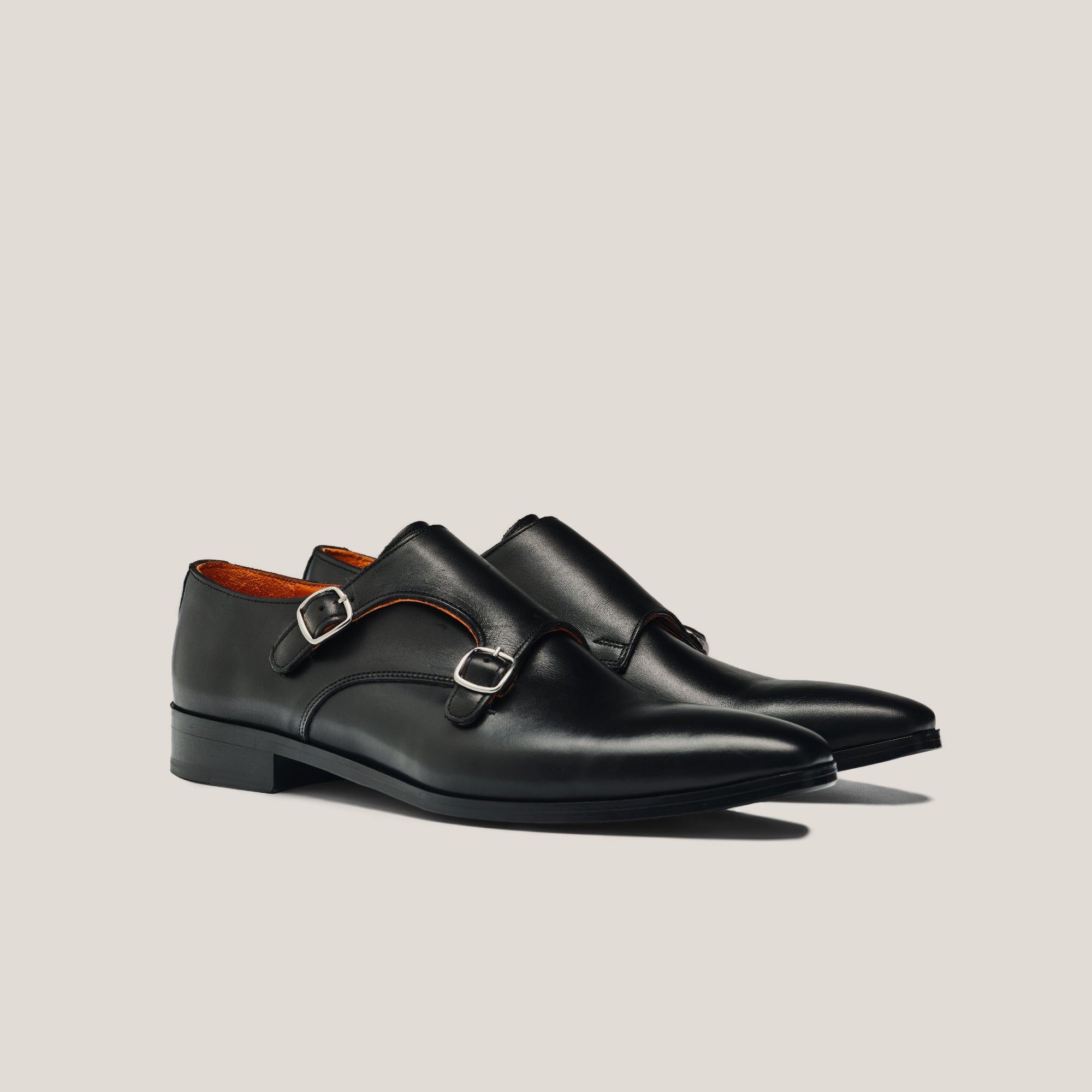 A pair of black leather double monk shoes with silver buckles.